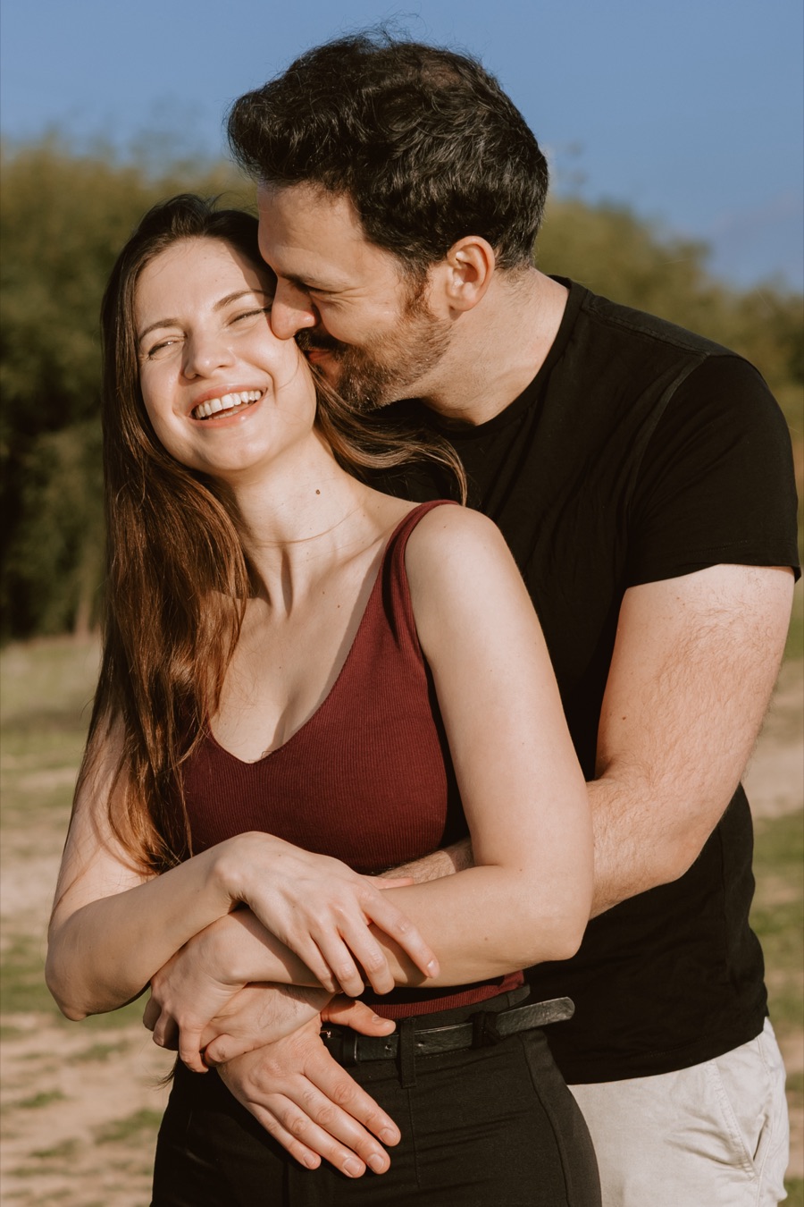 זוג מחובק, היא צוחקת והוא מנשק את הלחי