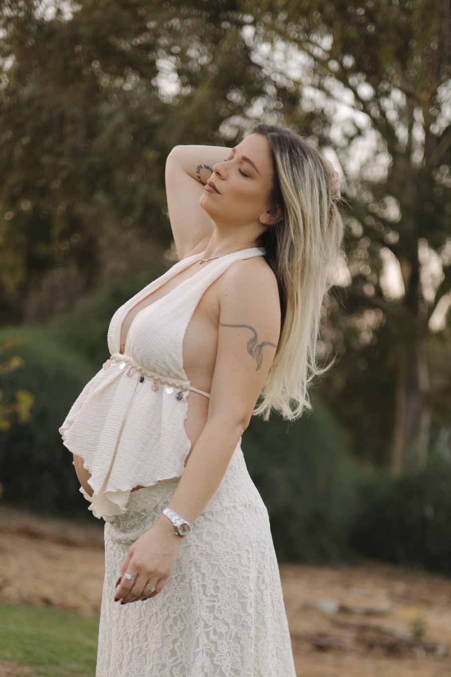 אישה בהריון בשמלה לבנה, יד בשיער