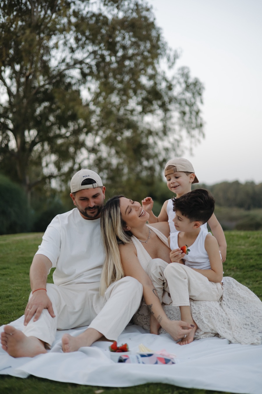 משפחה עם שני ילדים על שמיכה בדשא