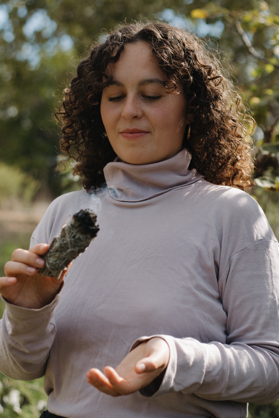 אישה בעיניים עצומות מחזיקה צרור מרווה